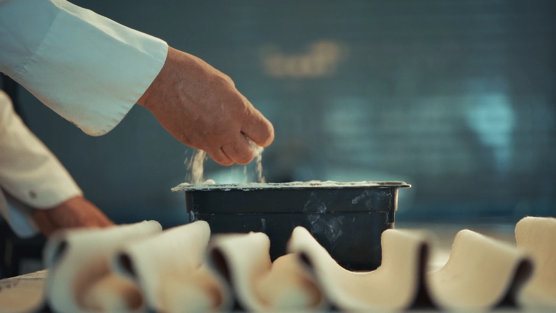 Farro ekşi maya filminde mutfak tezgâhına un serpen eller.